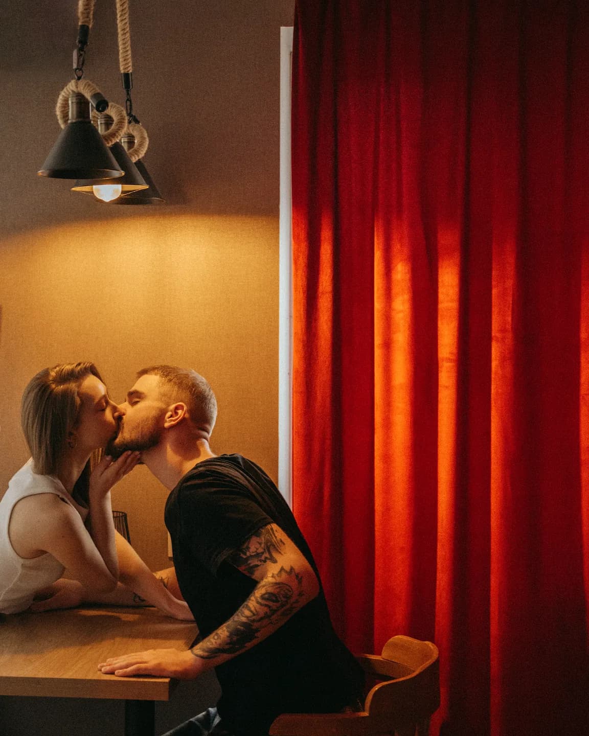 Нежный поцелуй пары на фоне заката, мягкие тона